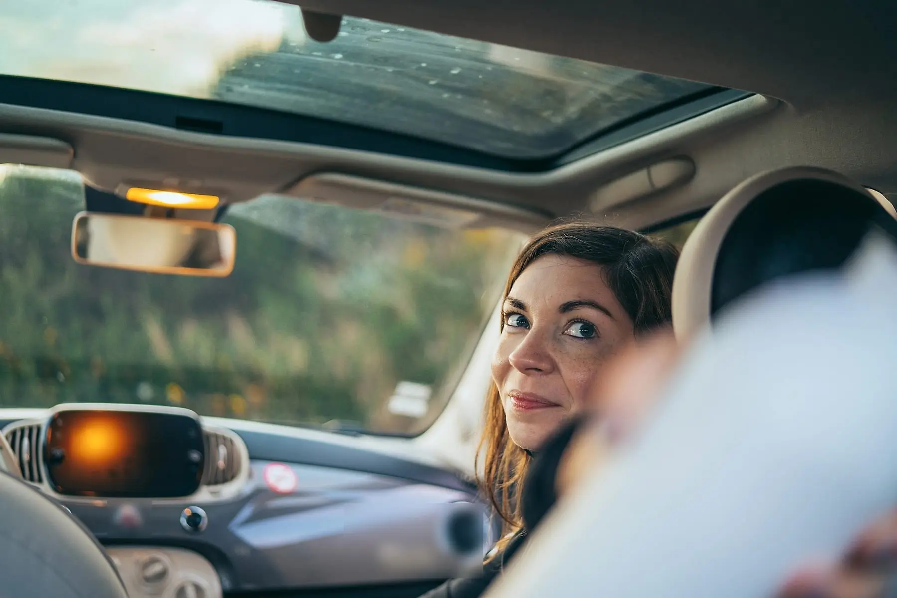 Conductrice souriante se retournant au volant de sa petite citadine