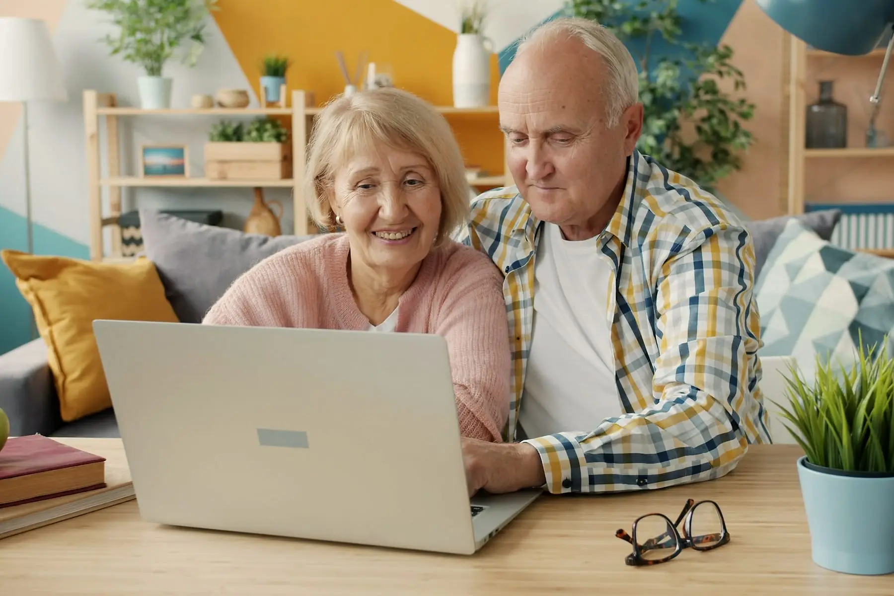 Couple de seniors souriants devant un ordinateur portable dans leur salon