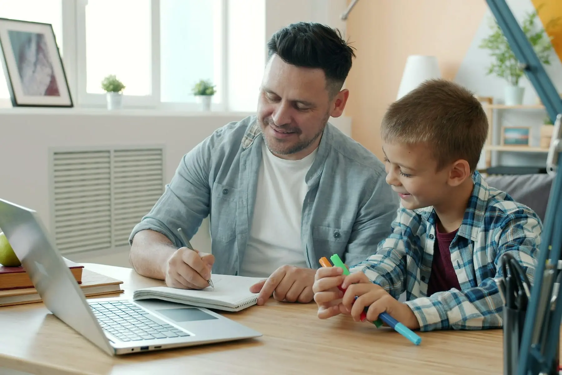 Père installé à son bureau avec son fils qui dessine à côté de lui