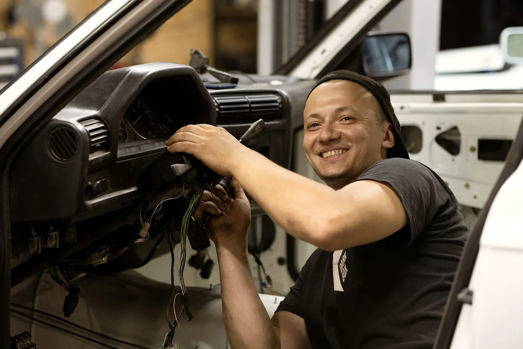 Mécanicien souriant travaillant sur le tableau de bord d'un véhicule