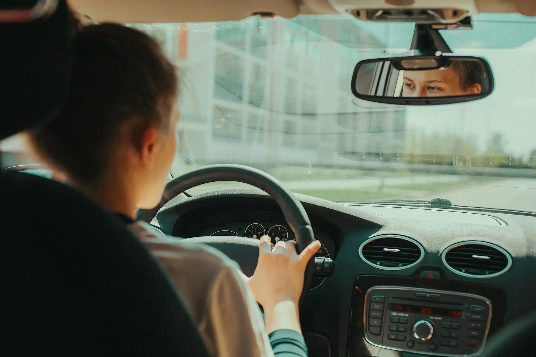 Homme au volant de sa voiture en ville, vu depuis l'habitacle