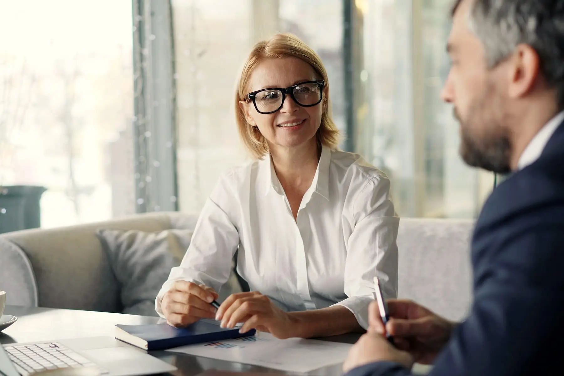 Cliente souriante face à son conseiller, des documents posés sur la table
